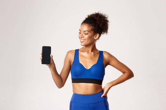 体育运动技术概念适合健康的非裔美国人女运动员很高兴显示智能手机屏幕白色背景