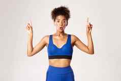 概念锻炼健身深刻的印象惊讶非裔美国人女运动员运动女孩指出手指相机白色背景
