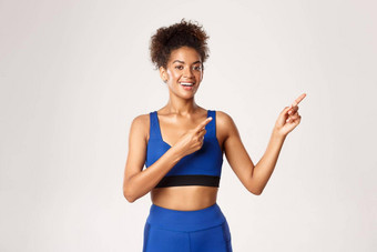概念锻炼健身健康的快乐非裔美国人女人运动员蓝色的运动服装指出手指上角落里微笑显示品牌