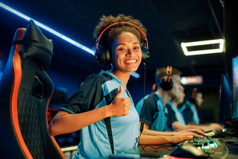 年轻的女人耳机玩电脑游戏互联网俱乐部