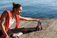 特写镜头自信女运动员伸展运动腿坐着码头培训