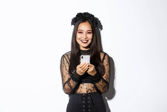 图像优雅的漂亮的浅黑肤色的女人女巫哥特花边衣服移动电话微笑相机站白色背景