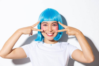 图像可爱的亚洲女人蓝色的假发<strong>显示卡</strong>哇伊和平手势微笑庆祝万圣节站白色背景