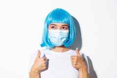 概念万圣节庆祝活动冠状病毒特写镜头快乐满意女孩医疗面具蓝色的假发显示竖起大拇指左批准