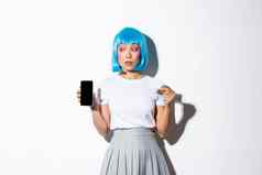 优柔寡断漂亮的亚洲女孩蓝色的假发不确定移动电话显示屏幕信贷卡站白色背景