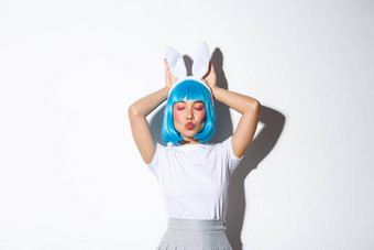 可爱的亚洲女孩蓝色的短假发兔子耳朵撅嘴卖弄风情的摆姿势白色背景万圣节服装