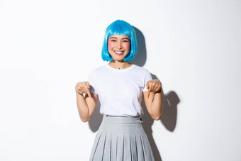 快乐的亚洲女人动漫风格装穿蓝色的假发微笑快乐指出手指显示广告站白色背景