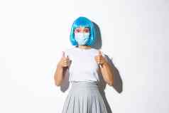 概念万圣节科维德流感大流行图像惊讶亚洲女人蓝色的假发医疗面具显示竖起大拇指批准