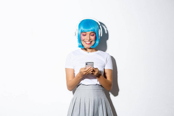 图像微笑亚洲女人蓝色的短假发智能手机屏幕快乐听播客音乐耳机