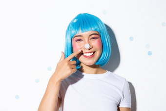 图像可爱的愚蠢的亚洲女孩五彩纸屑鼻子微笑快乐穿蓝色的假发万圣节聚会，派对