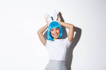 肖像可爱的微笑亚洲女孩蓝色的短假发兔子耳朵愚蠢的相机穿万圣节聚会，派对服装站白色背景