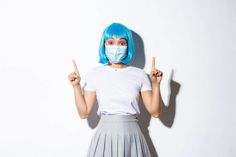 概念万圣节庆祝活动科维德流感大流行快乐亚洲女孩蓝色的假发医疗面具显示广告指出手指