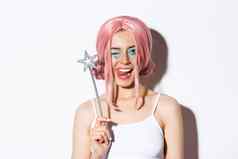 特写镜头美丽的时髦的女孩粉红色的假发穿服装仙女万圣节持有魔法魔杖显示舌头眨眼轻浮相机