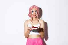 图像轻浮女孩粉红色的假发显示舌头诱惑持有美味的一块蛋糕站白色背景