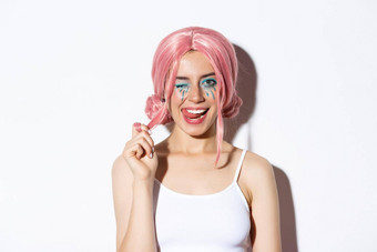 肖像时髦的有吸引力的女孩粉红色的假发穿装万圣节聚会，<strong>派</strong>对<strong>微</strong>笑眨眼相机站白色背景