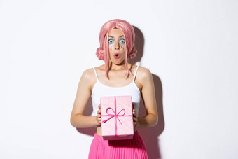 肖像惊讶有吸引力的女孩兴奋收到礼物生日穿粉红色的假发站白色背景