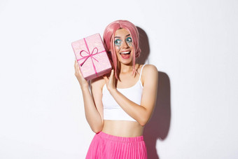 图像美丽的女孩粉红色的假发摇晃盒子生日礼物内部包装盒子站白色背景