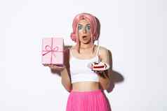 肖像惊讶美丽的女孩粉红色的假发收到生日礼物持有生日蛋糕微笑快乐站白色背景