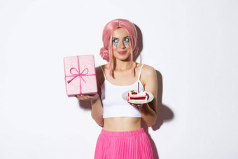 图像兴奋可爱的女孩粉红色的假发摇晃盒子礼物漫步内部持有一块生日蛋糕庆祝生日