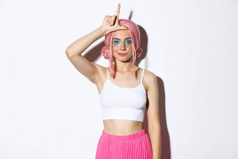 图像傲慢的年轻的时尚的女人粉红色的头发万圣节化妆显示<strong>失败者</strong>标志额头嘲笑站白色背景