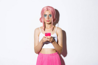 肖像有吸引力的聚会，派对女孩粉红色的假发明亮的化妆持有智能手机相机自信