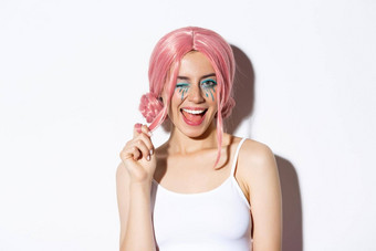 肖像时髦的有吸引力的女孩粉红色的假发穿装万圣节聚会，<strong>派</strong>对<strong>微</strong>笑眨眼相机站白色背景