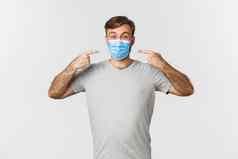 概念流感大流行冠状病毒社会距离图像英俊的男人。灰色的t恤推荐穿医疗面具科维德白色背景