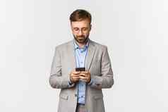 英俊的高加索人商人眼镜灰色的西装写作消息智能手机移动电话站白色背景