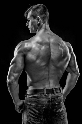 肌肉发达的健美运动员的家伙摆姿势黑色的背景