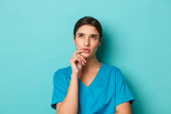 冠状病毒社会距离健康概念特写镜头深思熟虑的女医生穿实习医生风云上左角落里思考站蓝色的背景