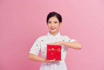 快乐的有吸引力的年轻的女人持有礼物盒子粉红色的背景