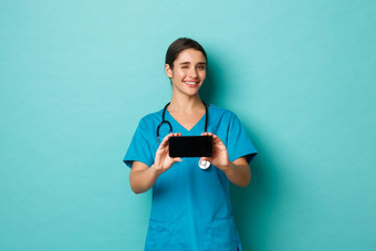 冠状病毒流感大流行社会距离概念图像微笑女医生实习医生风云眨眼显示智能手机屏幕水平站蓝色的背景