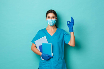 科维德流感大流行医学概念图像自信美丽的女医生医疗面具手套<strong>实习</strong>医生风云持有笔记本电脑显示标志蓝色的背景