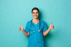 冠状病毒流感大流行社会距离概念图像有吸引力的自信女医生穿实习医生风云眼镜显示竖起大拇指微笑蓝色的背景