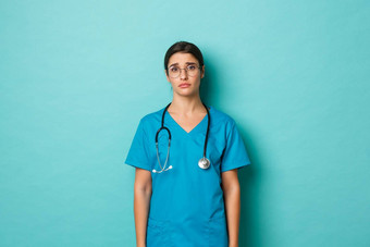 冠状病毒流感大流行社会距离概念图像伤心悲观的女医生穿<strong>实习</strong>医生风云眼镜站陷入困境的累了蓝色的背景