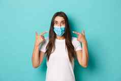 概念流感大流行科维德社会距离惊讶女孩白色t恤推荐穿医疗面具冠状病毒站蓝色的背景