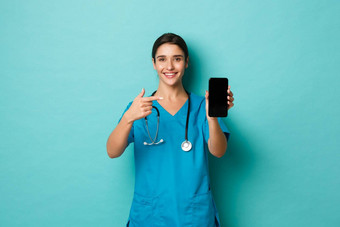 科维德流感大流行医学概念快乐的微笑医生实习医生风云指出手指移动电话显示应用程序站蓝色的背景