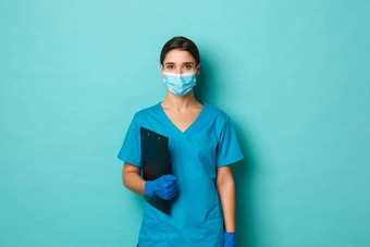 科维德流感大流行医学概念图像自信女医生医疗面具实习医生风云手套持有剪贴板站蓝色的背景