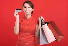 快乐中国人一年快乐年轻的女人显示信贷卡持有购物袋