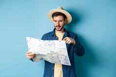 英俊的的家伙选择的地方指出sighseeing地图假期旅行夏天假期穿稻草他衬衫蓝色的背景
