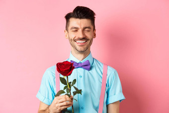 情人节一天浪漫概念浪漫的男人。红色的玫瑰日期情人站花俏的蝴蝶结粉红色的背景