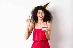 兴奋生日女孩庆祝使持有蛋糕交叉手指好运气站快乐白色背景