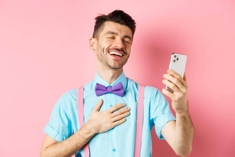 技术概念快乐高加索人男人。视频闲谈，聊天笑智能手机站粉红色的背景