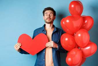 情人节一天概念男人。做梦真正的爱持有红色的心断路站浪漫的气球蓝色的背景