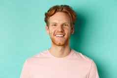 关闭红色头发的人有胡子的的家伙粉红色的t恤微笑白色完美的牙齿相机站绿松石背景