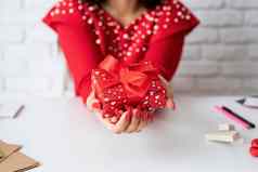 年轻的浪漫的女人红色的衣服持有礼物情人节一天白色砖墙背景
