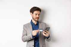 在线购物微笑商人支付信贷卡智能手机发送钱站西装白色背景
