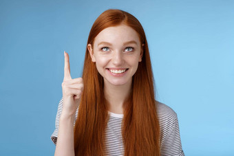 感兴趣活泼的快乐微笑红色头发的人欧洲女孩指出指数手指逗乐检查有趣的出售假期促销提供站感兴趣激动蓝色的背景