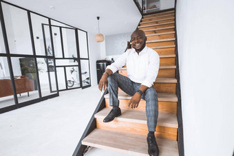 快乐年轻的成功的商人购买房子非洲式发型美国坐在楼梯大厅公寓微笑概念个人增长成功克服困难