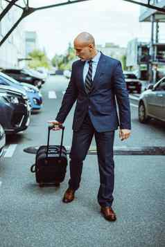 秃商人走机场停车很多手提箱停汽车商人西装手提箱业务旅行男人。走在户外行李确定自信